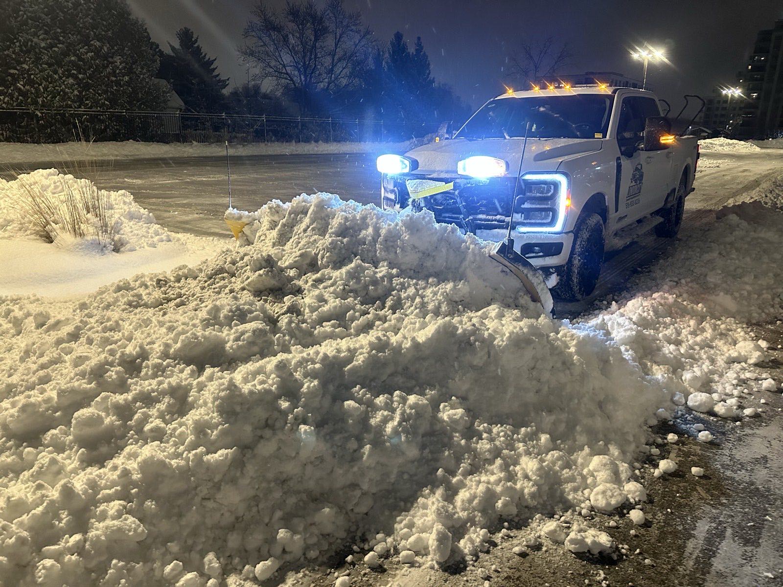 Plow truck pushing a snow bank back on a commercial property
