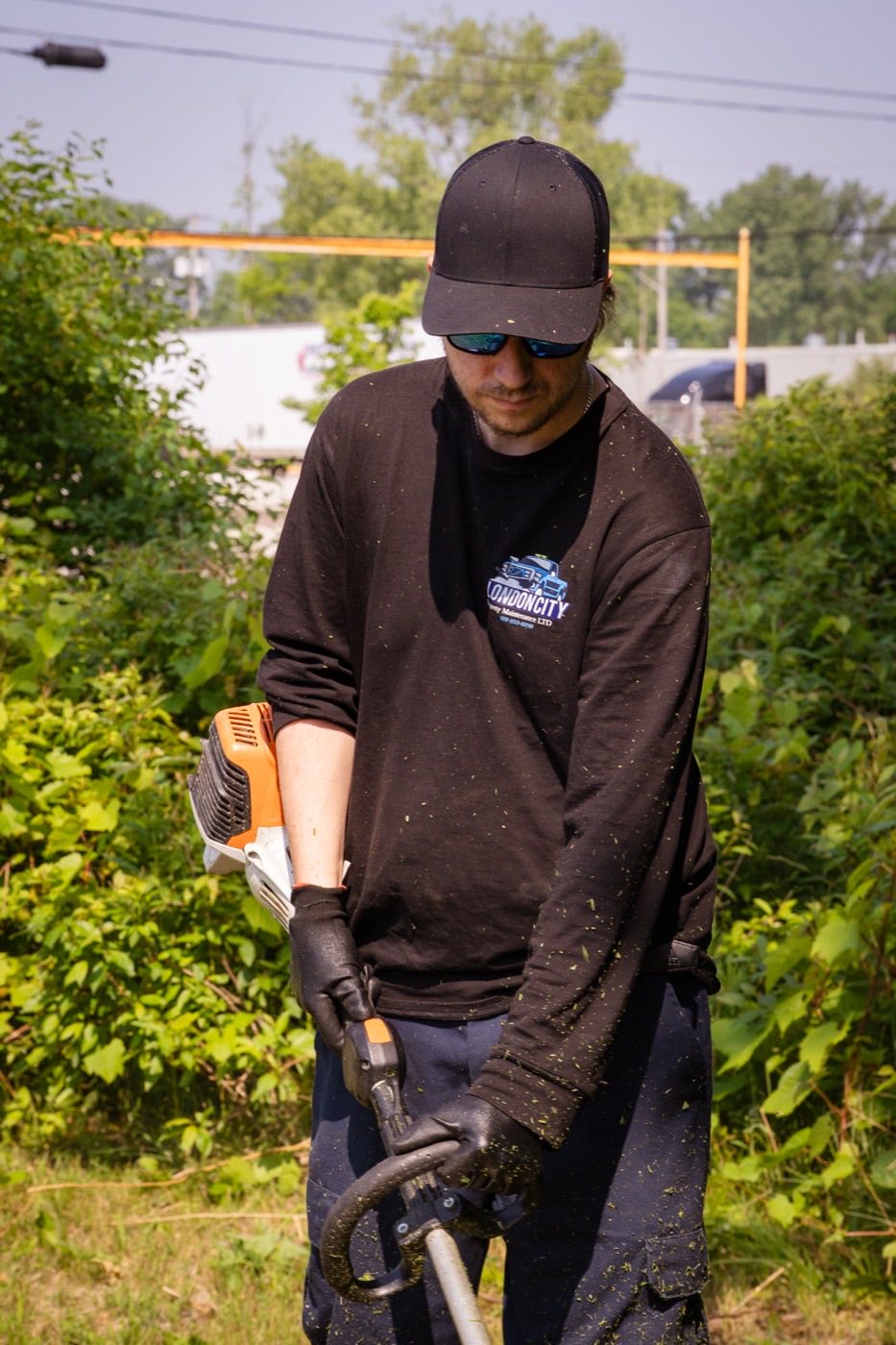 Crew member clearing overgrowth with a line trimmer